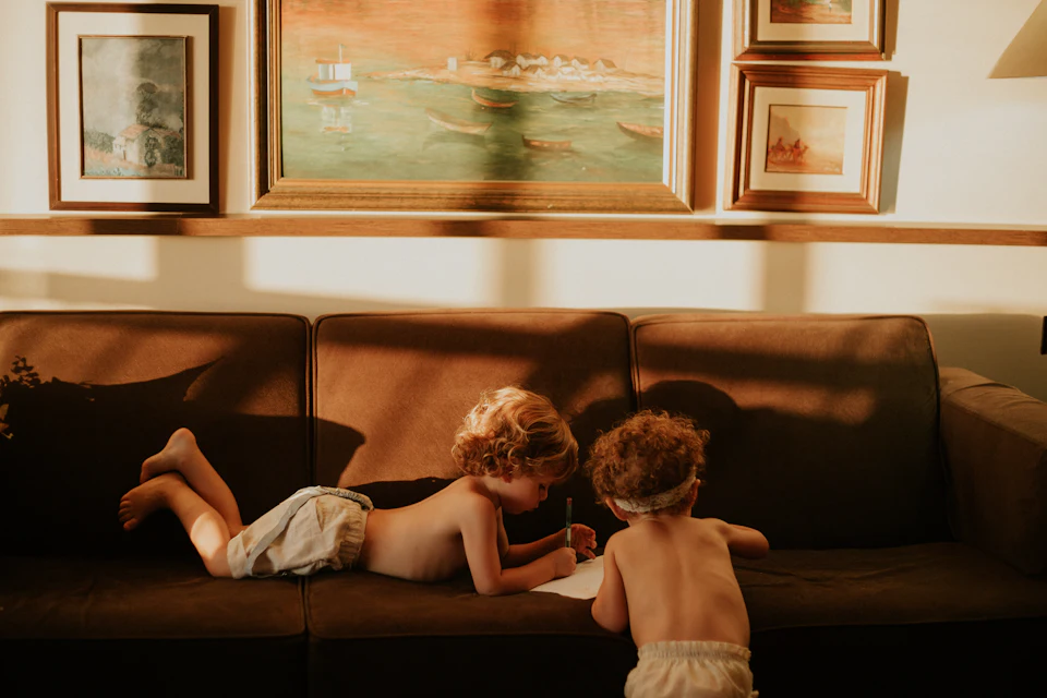 Due bambini sul divano di sera, ripresi di spalle