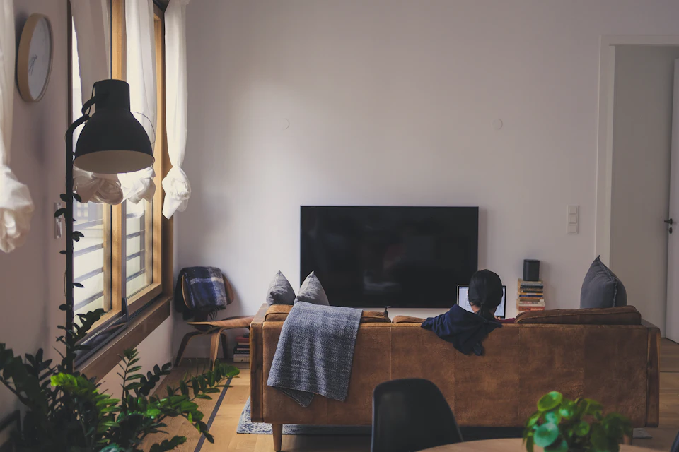 Salotto accogliente con divano, coperta e televisore spento