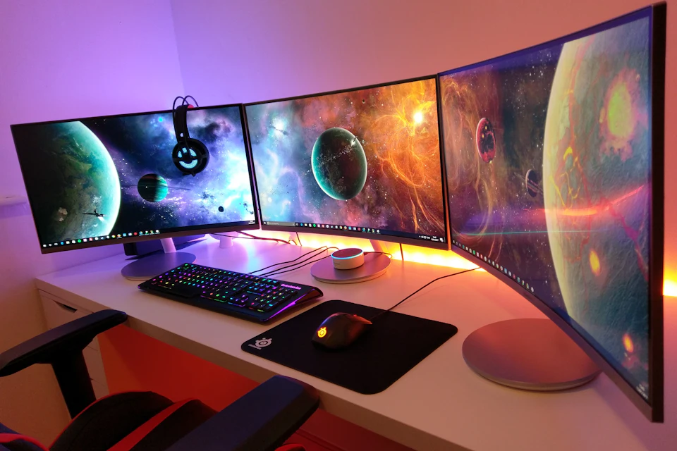 Scrivania con tre monitor curvi e tastiera