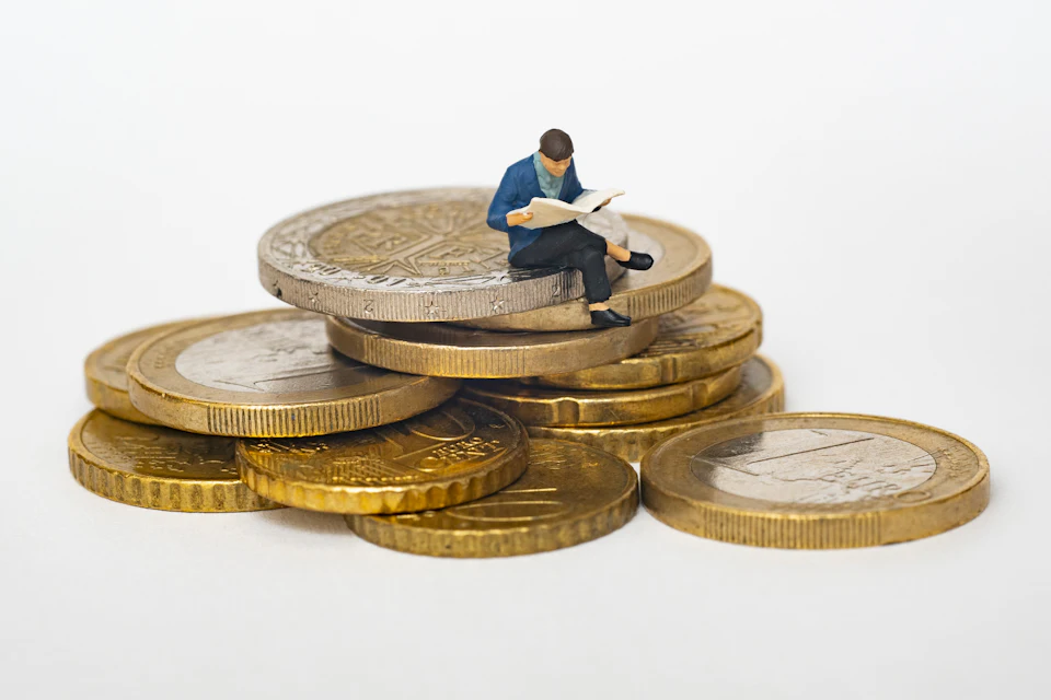 Piccola figura seduta su una pila di monete da euro